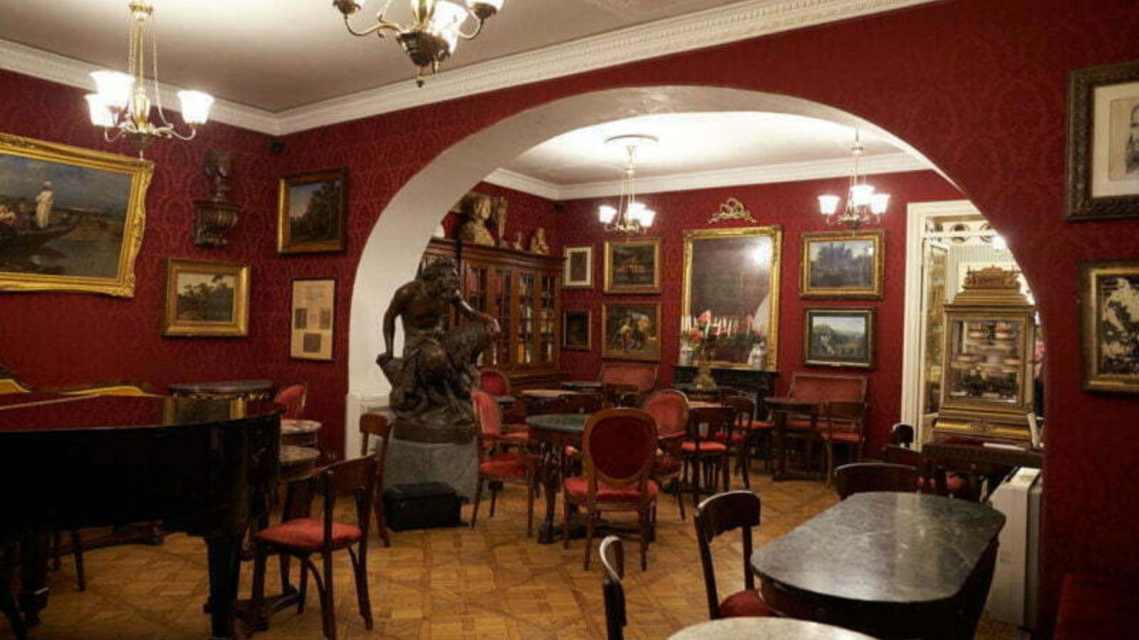 bức tượng nghệ thuật và nhiều bức tranh ảnh trong quán Caffe Greco, Rome, Ý với tone màu đỏ đô chủ đạo