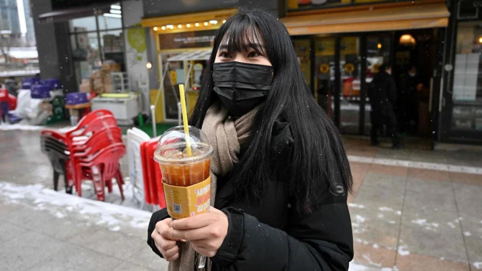 bạn nữ cầm ly cà phê lạnh trong thời tiết giá rét
